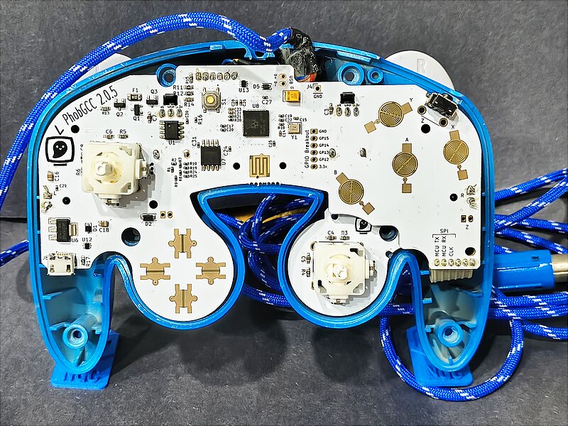 A PhobGCC 2.0.5 board installed in an opened GameCube controller, with both stickboxes, the tactile Z switch and a blue paracord cable visible.